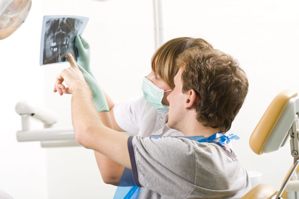 a young man examining a panoramic radiography with his dentist.