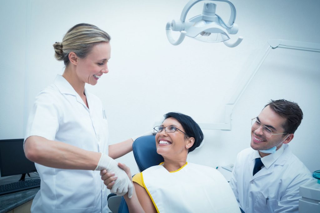 alternate benefit clause - female dentist shaking hands with woman in the dentists chair