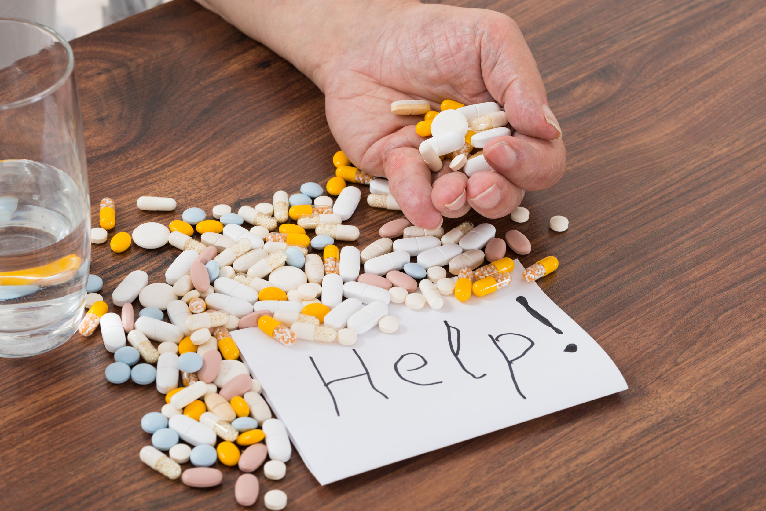 person holding pills in hand with help text on paper