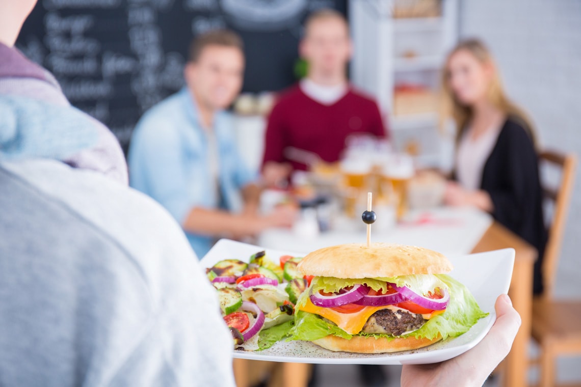 person-holding-white-plate-with-cheeseburger-and-salad