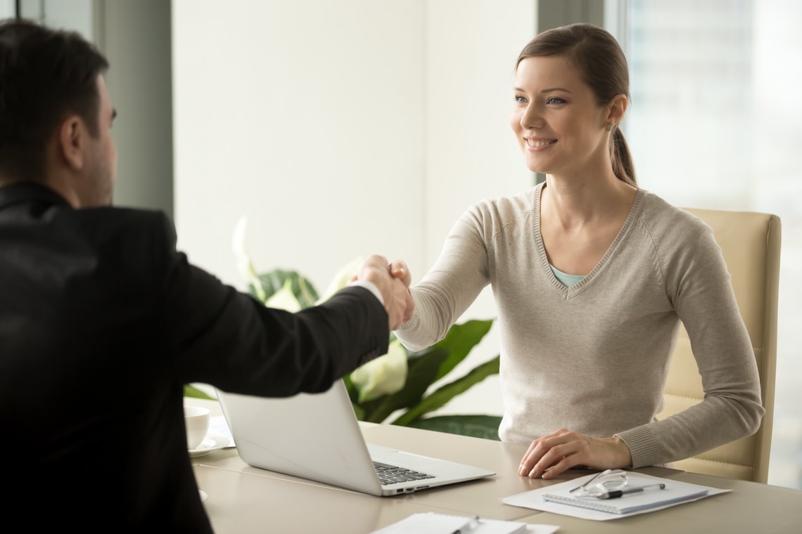 smiling-female-company-leader-welcoming-with-handshake-male-business-partner-before-or-after-busines