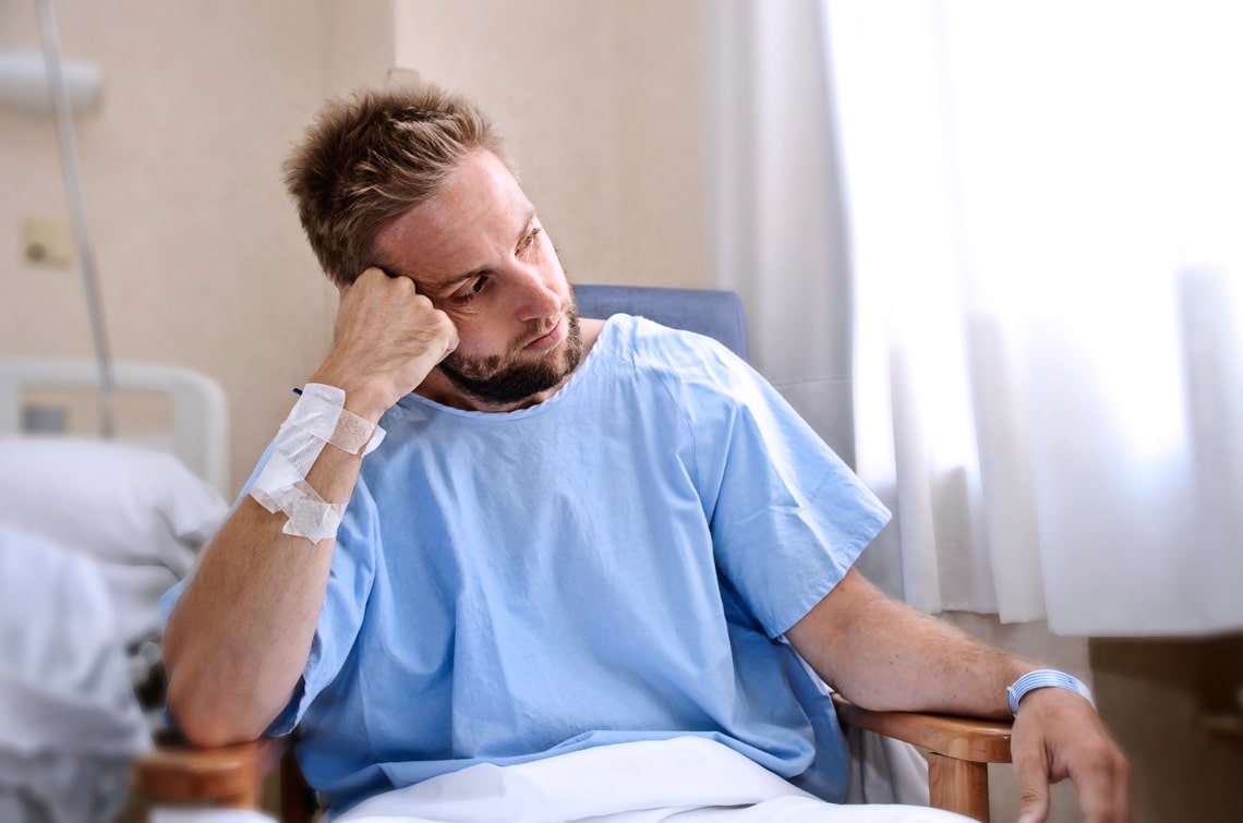 young-injured-man-in-hospital-room-sitting-alone-in-pain-looking-negative-and-worried-for-his-bad