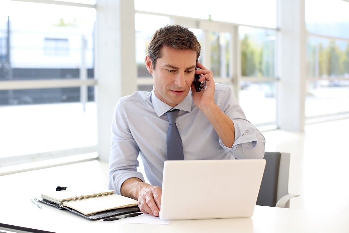 portrait-of-businessman-talking-on-mobile-phone-in-office