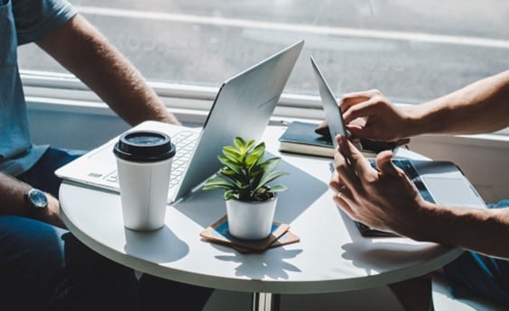 Two people working on laptops at a cafe