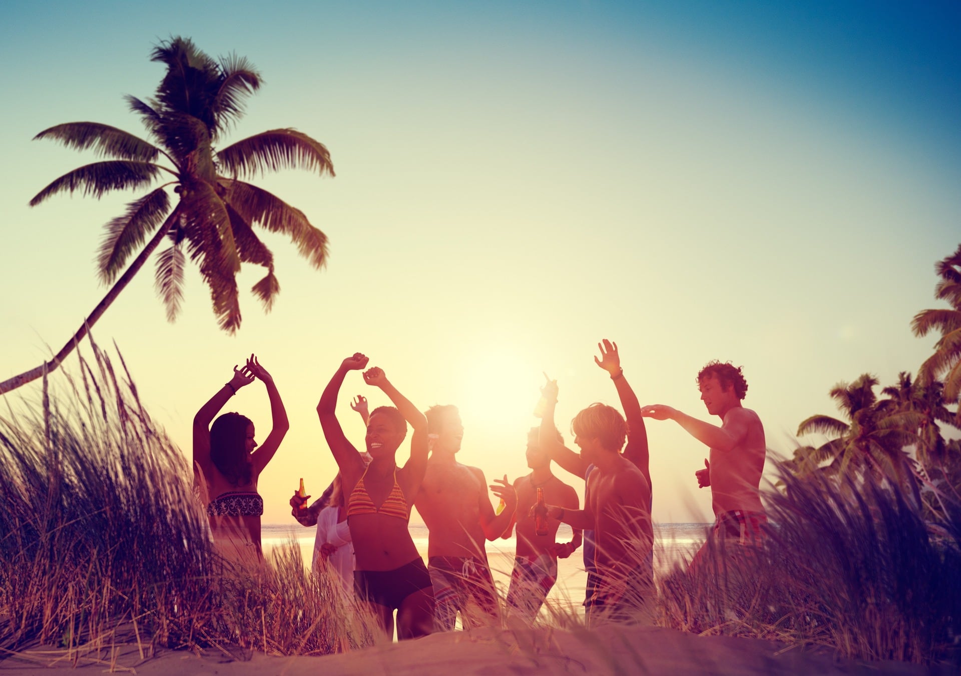 Group of young people partying on the beach during a buddymoon