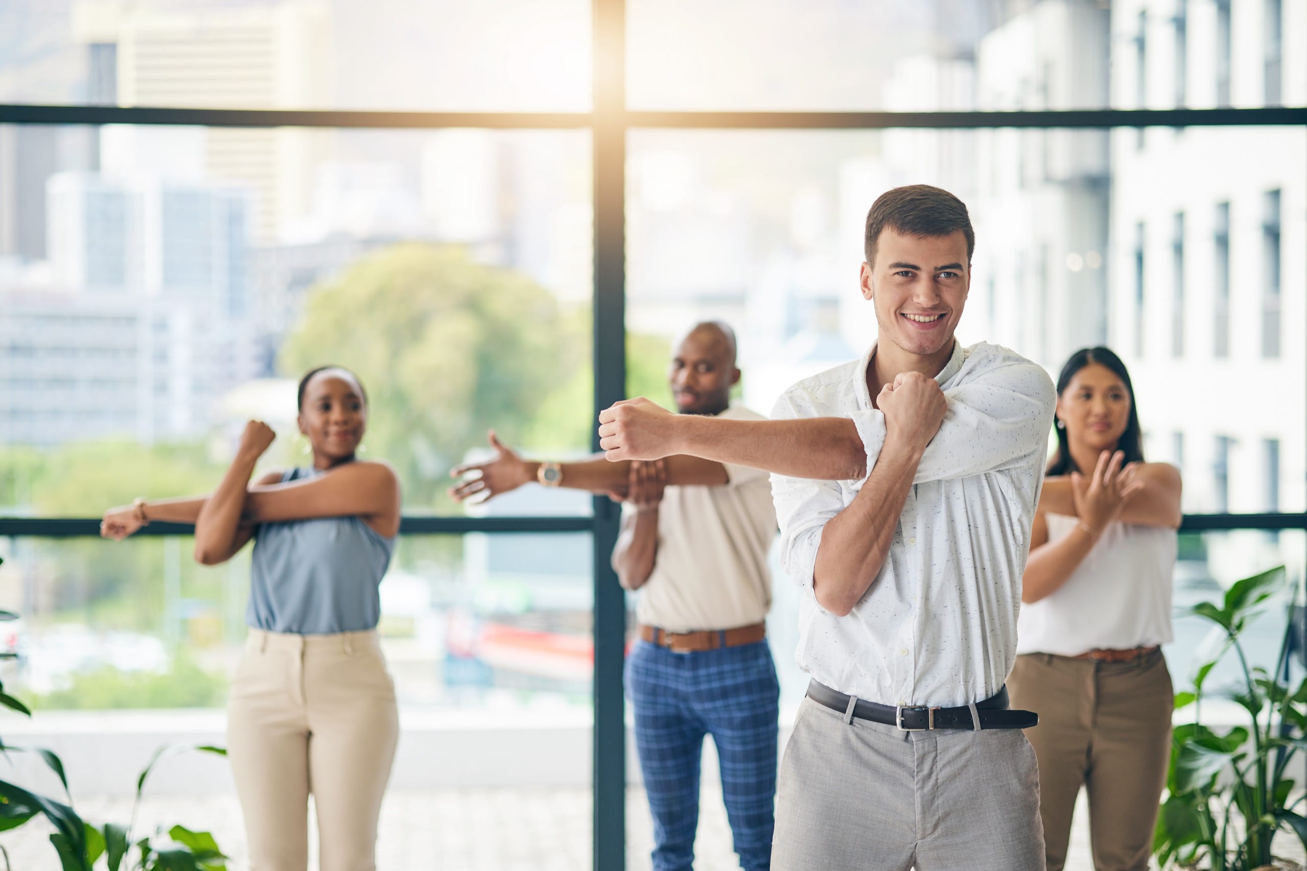 Workout, stretching and a group of business people in the office to exercise for health or mobility together. Fitness, wellness and coach training an employee team in the workplace for a warm up
