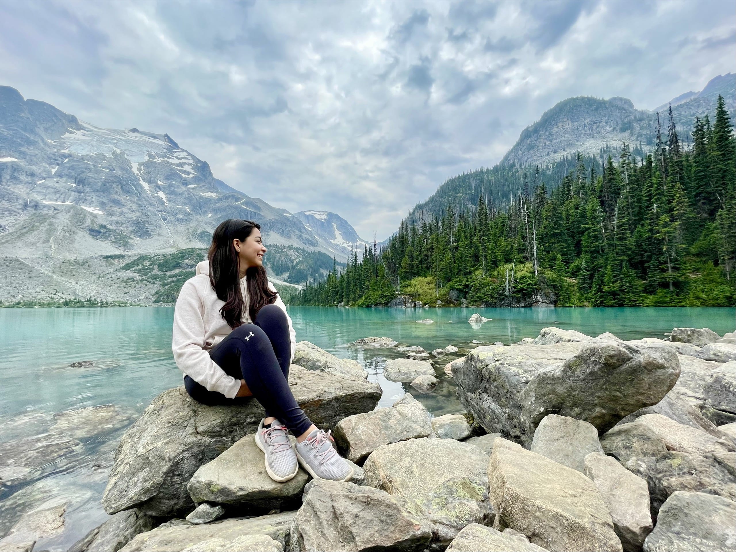 Woman sitting on the rocks in front of a lake an the Canadian Rocky Mountains