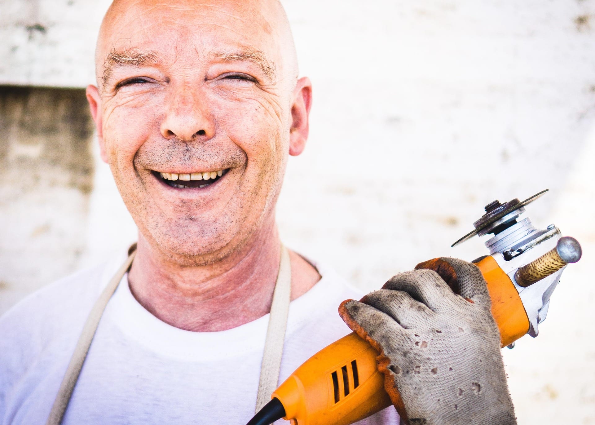 Old smiling man holding angle grinder